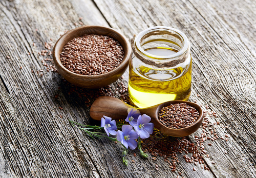Flax oil with flax seeds on wooden background