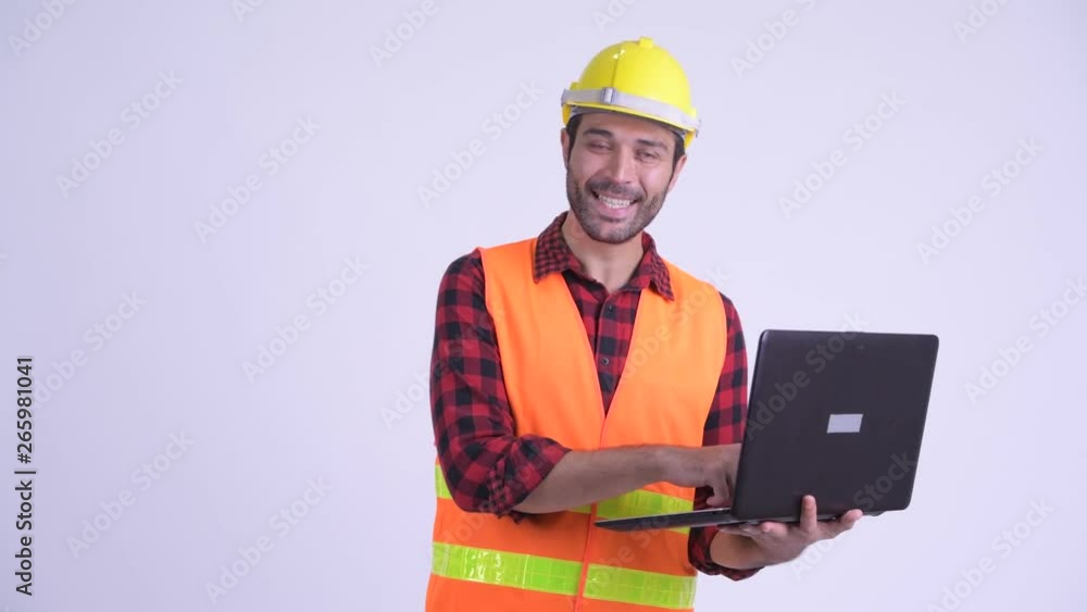 Happy bearded Persian man construction worker using laptop and giving thumbs up Happy bearded Persian man construction worker using laptop and giving thumbs up