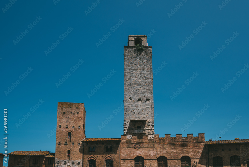 View of the city towers on the famous Piazza della Cistern in the historic city of San Gimignano on a sunny day, Tuscany, Italy