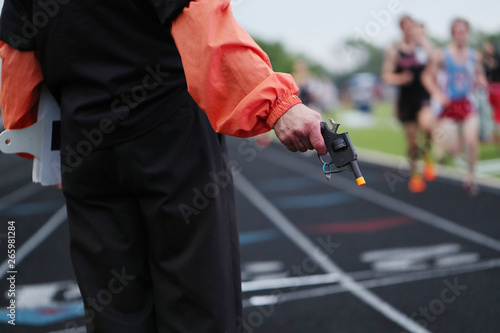 A starter gun signals the final lap in a high school track meet