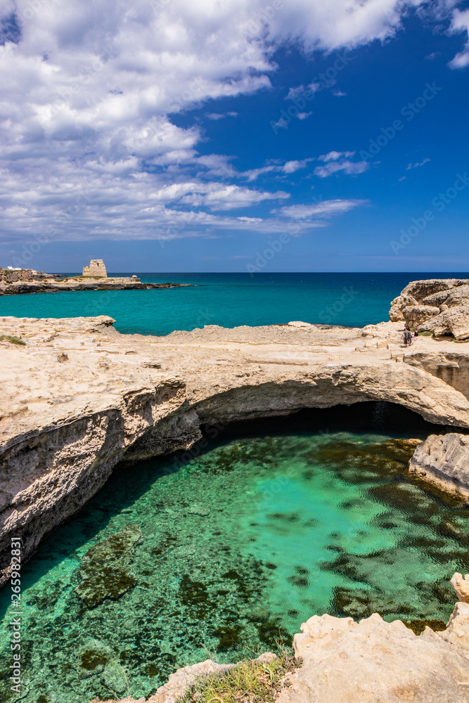 Archaeological site and tourist resort of Roca Vecchia, Puglia, Salento, Italy. Turquoise sea, clear blue sky, rocks, sun, in summer. The Cave of Poetry. The lookout tower in the background.