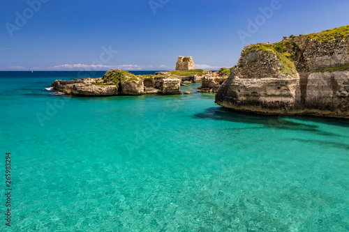 The important archaeological site and tourist resort of Roca Vecchia  in Puglia  Salento  Italy. Turquoise sea  clear blue sky  rocks  sun  in summer. Messapic walls and ruins of the watch tower