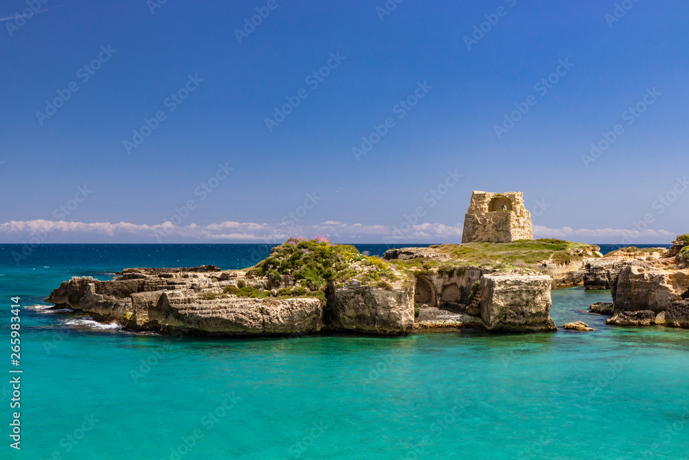 The important archaeological site and tourist resort of Roca Vecchia, in Puglia, Salento, Italy. Turquoise sea, clear blue sky, rocks, sun, in summer. Messapic walls and ruins of the watch tower