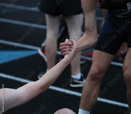 A high school track participant helps up a competitor after a race. 