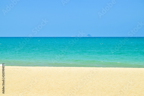 Stripes of blue sky and green ocean and yelllow sand on beach