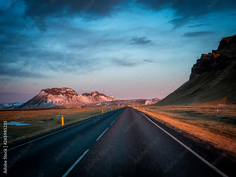 Modern car riding on asphalt countryside road towards magnificent snowy mountains during trip through Iceland
