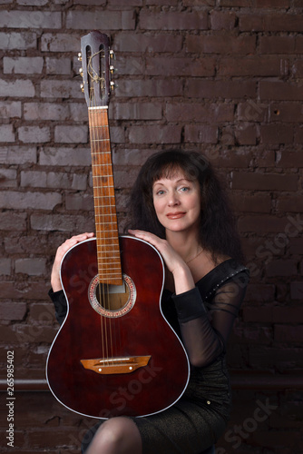 Beautiful adult woman playing guitar in the Studio.