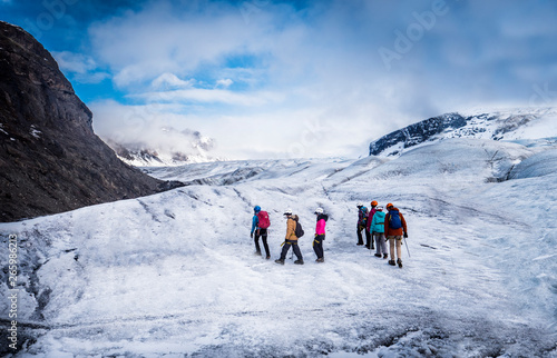 Back view of professional mountaineers in warm clothes walking on icy surface glacier by snowy mountain in Iceland © theartofphoto