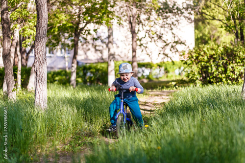 four-year-old boy in a hat quickly rides on a running bike on the path in the Park