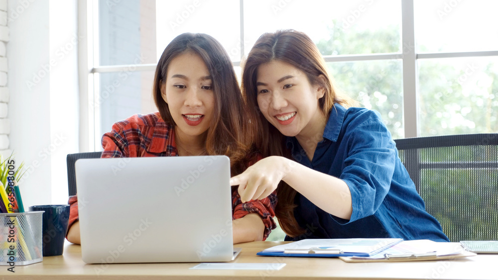 Two young asian women working with laptop computer at home office with happy emotion moment, working at home, small business, office casual lifestyle concept Two young asian women working with laptop computer at home office with happy emotion moment, working at home, small business, office casual lifestyle concept