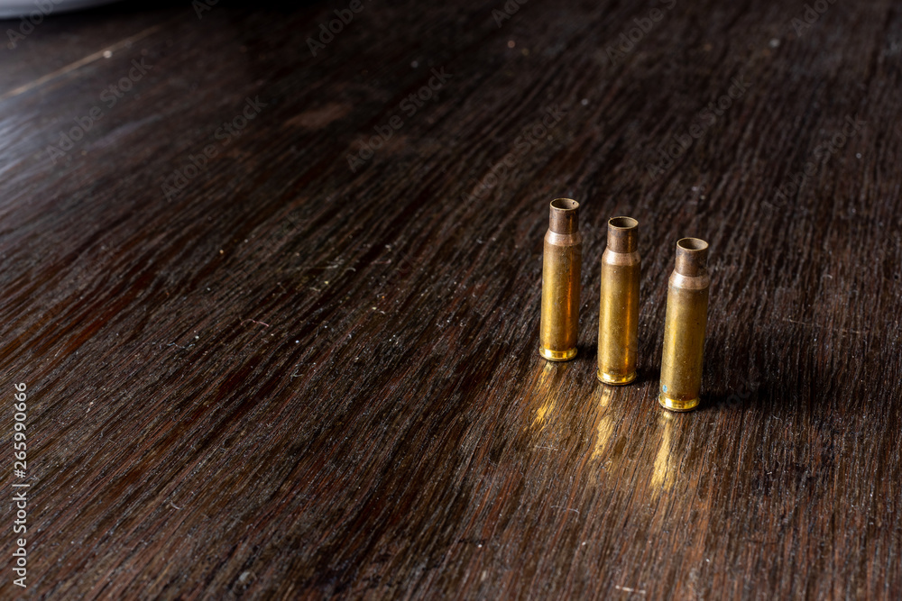 Empty bullet casings on a dark, wooden table. Empty bullet casings on a dark, wooden table.