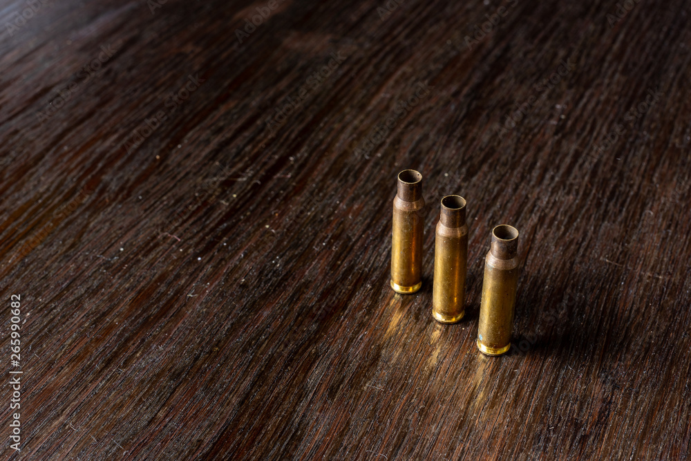 Empty bullet casings on a dark, wooden table. Empty bullet casings on a dark, wooden table.