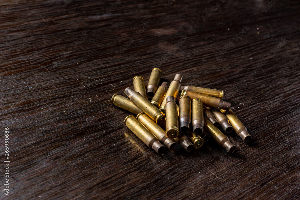 Empty bullet casings on a dark, wooden table. Empty bullet casings on a dark, wooden table.