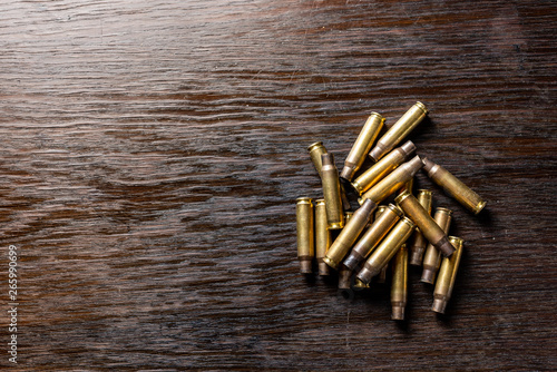 Leinwand Poster Empty bullet casings on a dark, wooden table.