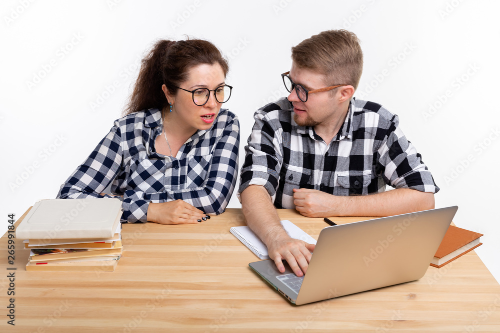 Education, students, people concept - funny couple of teens in glasses look like nerds sitting at the table Education, students, people concept - funny couple of teens in glasses look like nerds sitting at the table