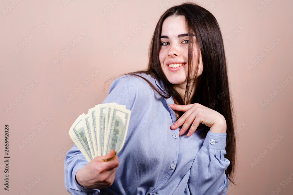 Savings, earning, money and banking, purchases and shopping. Beautiful young woman joyfully holding in her hand a lot of dollars Savings, earning, money and banking, purchases and shopping. Beautiful young woman joyfully holding in her hand a lot of dollars
