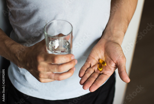  vitamins and a glass of water in the hands of a man