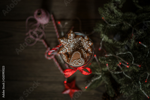 Fototapeta Naklejka Na Ścianę i Meble -  Christmas gift with homemade gingerbread cookies, nuts and chocolates. Glass jar, fir branches, Christmas spices and decor. Winter holidays, New Year or Christmas concept. Top view with copy space.