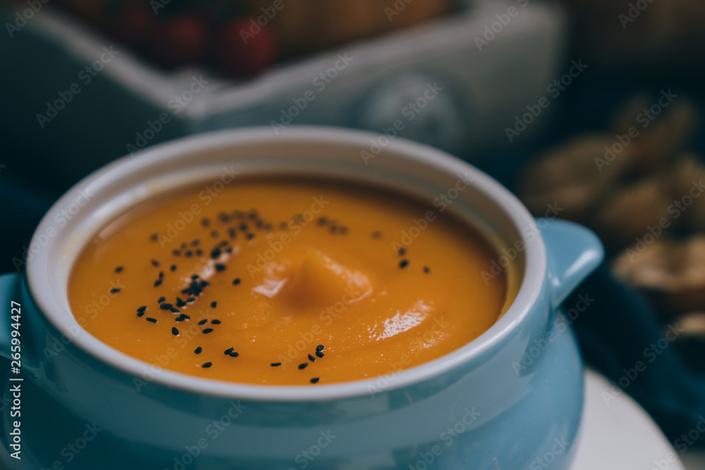 Homemade autumn butternut squash soup with bread. Roasted pumpkin and carrot soup with cream and pumpkin seeds on white wooden background. Concept of healthy eating food. Copy space. Toned image. Homemade autumn butternut squash soup with bread. Roasted pumpkin and carrot soup with cream and pumpkin seeds on white wooden background. Concept of healthy eating food. Copy space. Toned image.