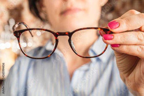 female hand holding a brown framed glasses photo