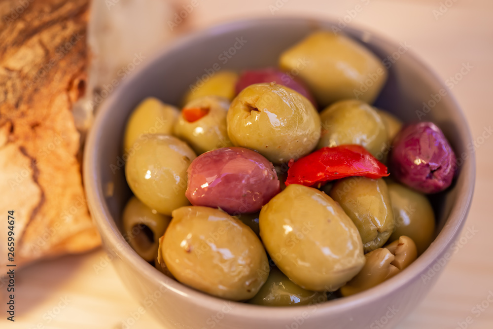 Olives stuffed, red pepper and homemade bread. Multicolored olives in a small bowl on a wooden table. Blurry background. Closeup. Soft focus. Top view. Olives stuffed, red pepper and homemade bread. Multicolored olives in a small bowl on a wooden table. Blurry background. Closeup. Soft focus. Top view.