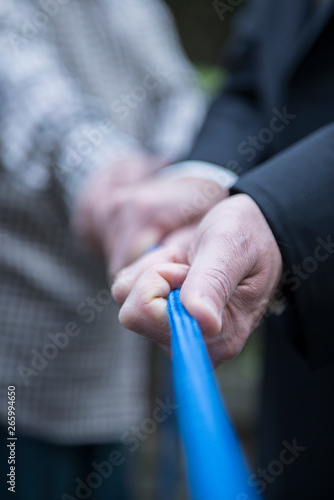 Pull together on a blue rope, human hands of male persons, business