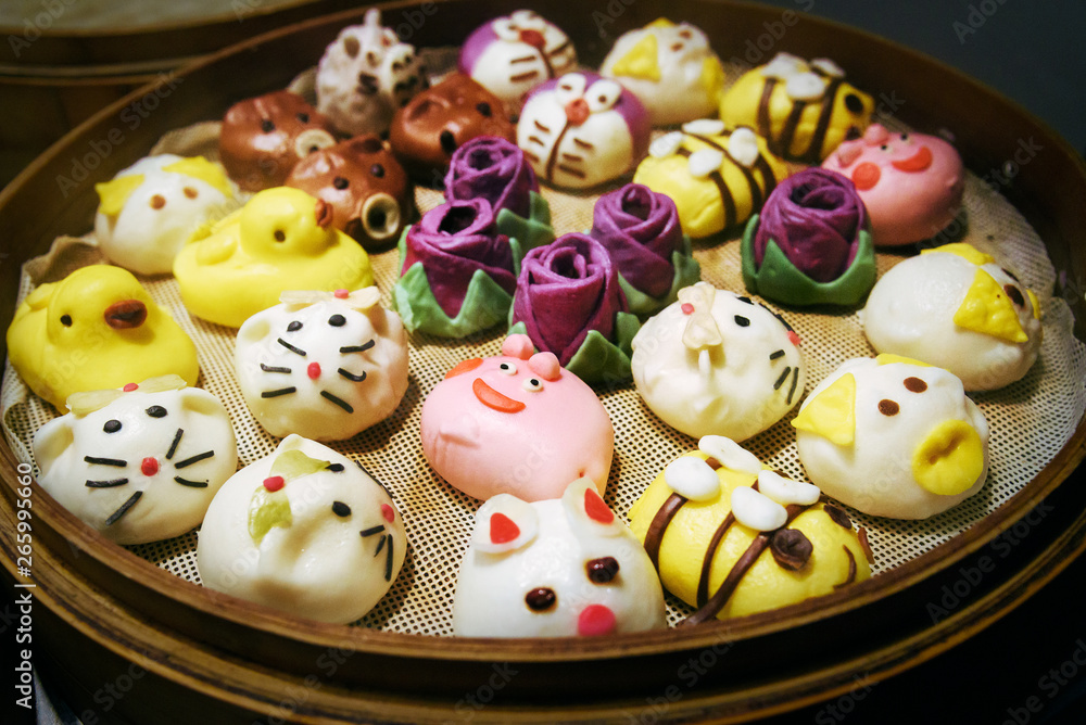 Steamed buns made in the shape of cartoons and animals. Dim sum  steamed in bamboo steamer. Chinese traditional cuisine.