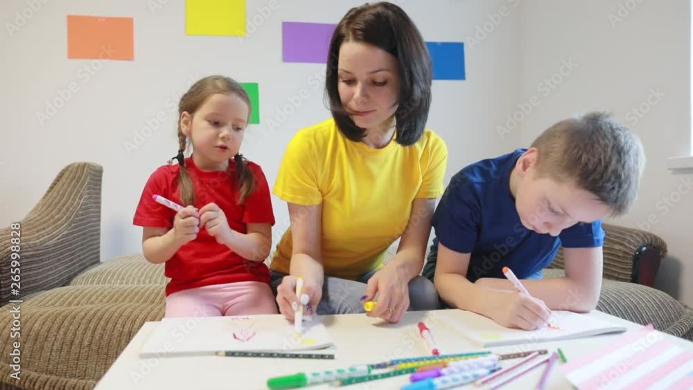 A caring mother teaches two of her children to draw the flag of America with colored pencils and felt-tip pens for America’s Independence Day. A caring mother teaches two of her children to draw the flag of America with colored pencils and felt-tip pens for America’s Independence Day.