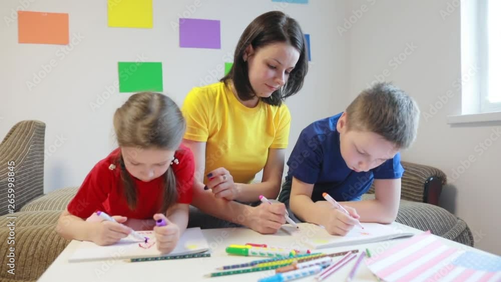 A caring mother teaches two of her children to draw the flag of America with colored pencils and felt-tip pens for America’s Independence Day. A caring mother teaches two of her children to draw the flag of America with colored pencils and felt-tip pens for America’s Independence Day.