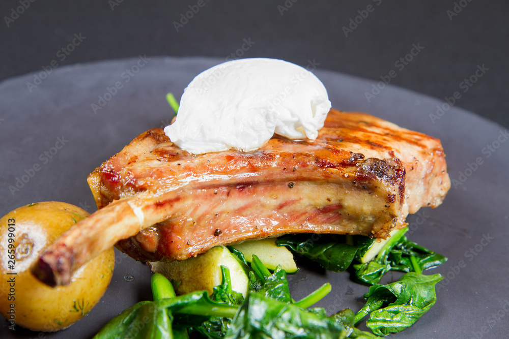 Organic apple pork steak served with baked potatoes,poached egg, spinach and oven baked zucchini