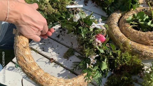 Mother and daughter tie easter wreaths, spring wreaths, summer wreaths outdoors in sunshine and are happy