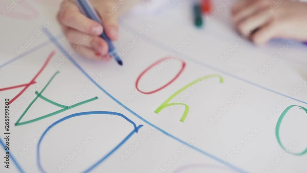 Child drawing. Hand of a child writing letters on white paper Child drawing. Hand of a child writing letters on white paper