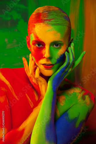 Fashion portrait of beautiful girl with bright pigment, creative art make-up, abstract face art on colors background