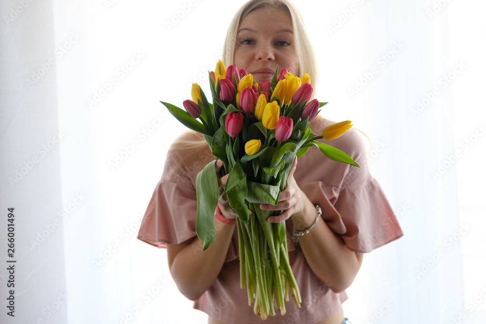 Beautiful blond girl posing for photo with flowers