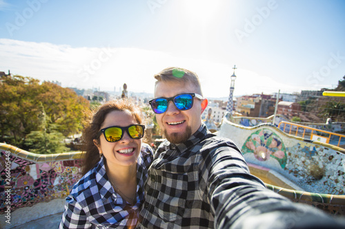 Photography Funny young couple looking at camera taking photo with smart phone smiling in Park Guell, Barcelona, Spain