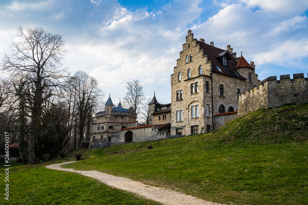 Germany, German castle lichtenstein behind ancient walls of stone next to green meadow