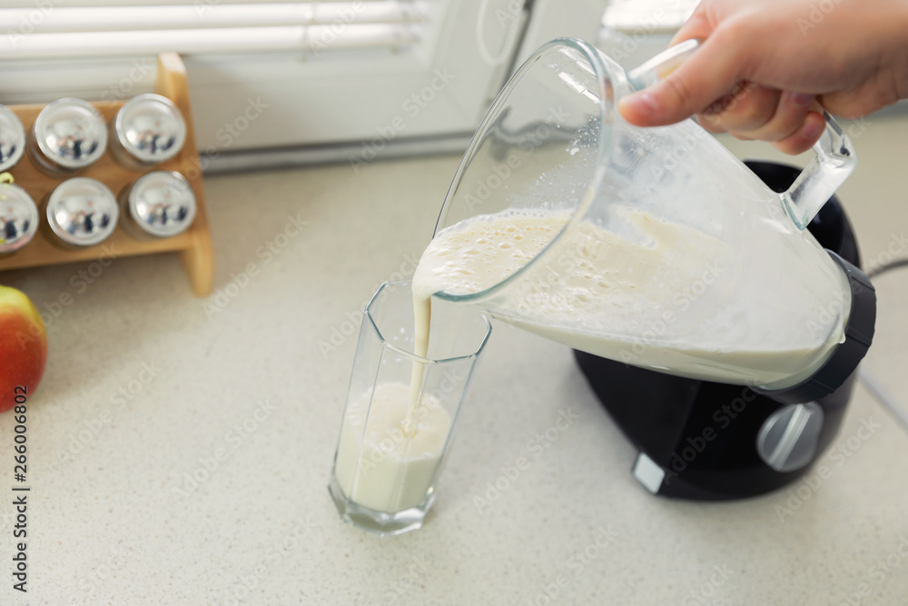 A young man prepares a smoothie of milk and fresh fruit for breakfast. He leads a healthy lifestyle. A young man prepares a smoothie of milk and fresh fruit for breakfast. He leads a healthy lifestyle.
