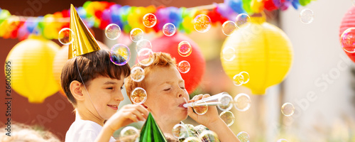 Boys playing with soap bubbles during birthday party for children