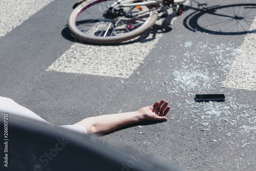 Human's hand on street next to broken glass and mobile phone, car crash concept