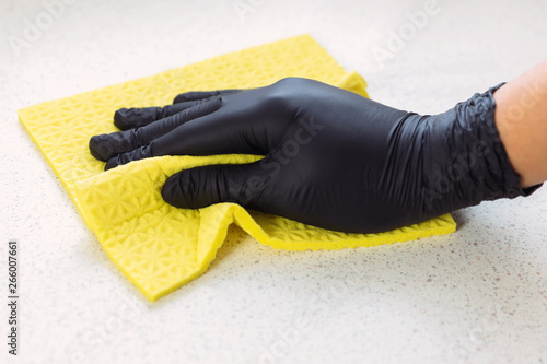 The man in black gloves cleans up in the kitchen, he wipes the table with a rag. photo