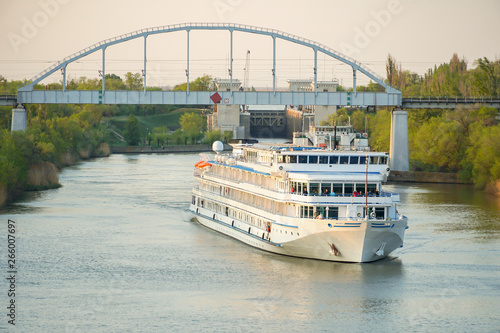 Cruise liner with tourists passes by the cargo ship and under the railway bridge. Volga-Don Canal. Volgograd.