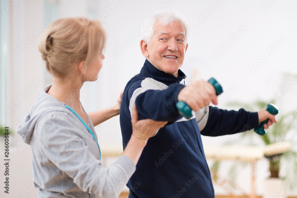 Senior man after stroke at nursing home exercising with professional physiotherapist