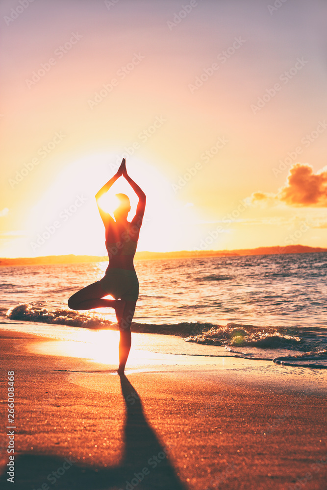 Yoga wellness retreat class on morning sunrise beach landscape. Silhouette of girl standing in tree pose meditation vertical background. - obrazy, fototapety, plakaty 