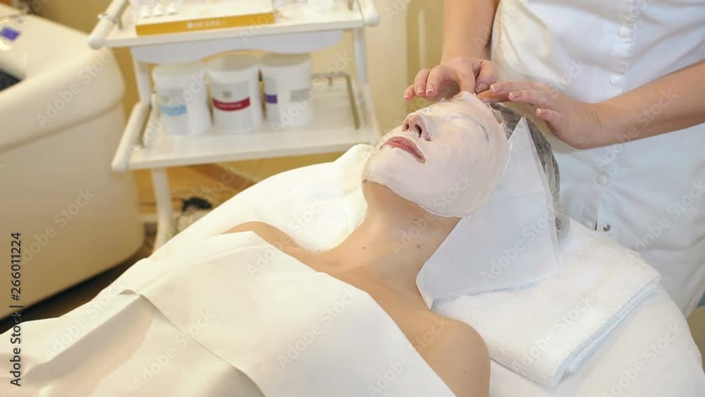 Beautician removes a clay mask from the face of a young girl in the Spa salon. Beautiful young girl at the beautician does the spa procedures, facial massage and mask for the skin. Slow motion. Beautician removes a clay mask from the face of a young girl in the Spa salon. Beautiful young girl at the beautician does the spa procedures, facial massage and mask for the skin. Slow motion.