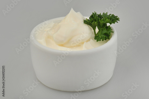 Mayonnaise and parsley in a bowl on an isolated gray background