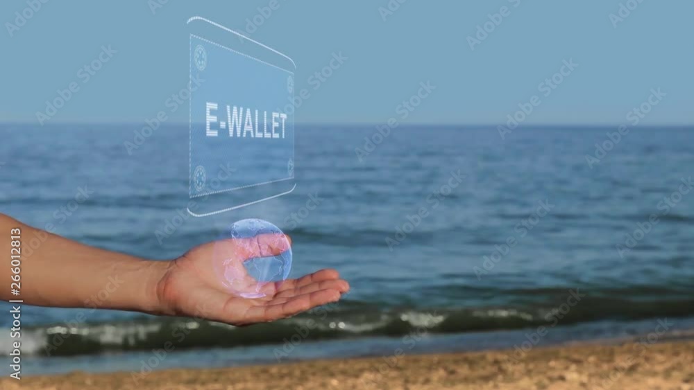 Male hands on the beach hold a conceptual hologram with the text E-wallet. A man with a holographic technology on the background of the sea Male hands on the beach hold a conceptual hologram with the text E-wallet. A man with a holographic technology on the background of the sea