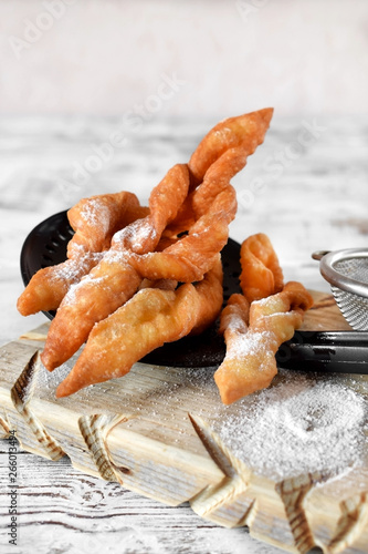 Homemade golden khvorost cookies on skimmer on the white table photo