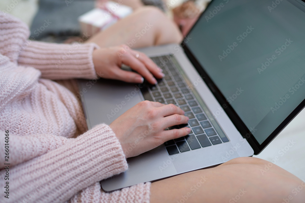 Naklejka premium Christmas online shopping. Woman buys presents, prepare to xmas eve. Female with laptop, copy space on screen. Hot coffee, spice and almond cakes on tray. Cozy blanket. Toned image. Soft focus.