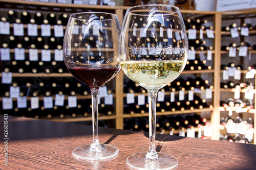 white and red wine in glasses on the background of bottles
