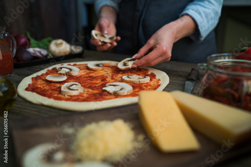Pizza art. The process of making pizza. Raw dough for pizza with ingredients and spices on table. Traditional Italian pizza and vegetables on a dark wooden background. Pizza menu. Soft focus.